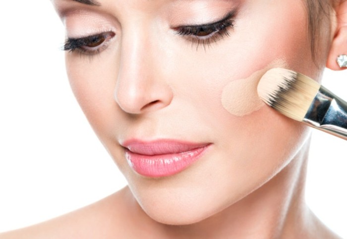 Makeup artist applying liquid tonal foundation on the face of the woman