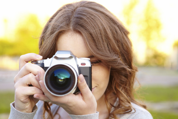 Young woman uses digital slr photocamera.