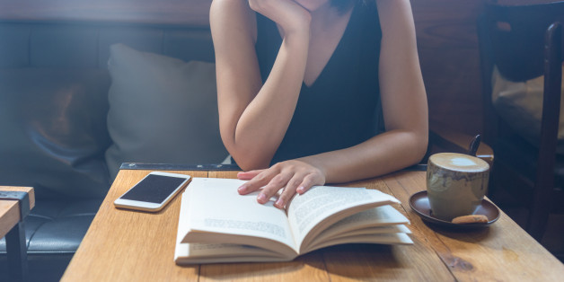 Woman reading book with her chin on hand